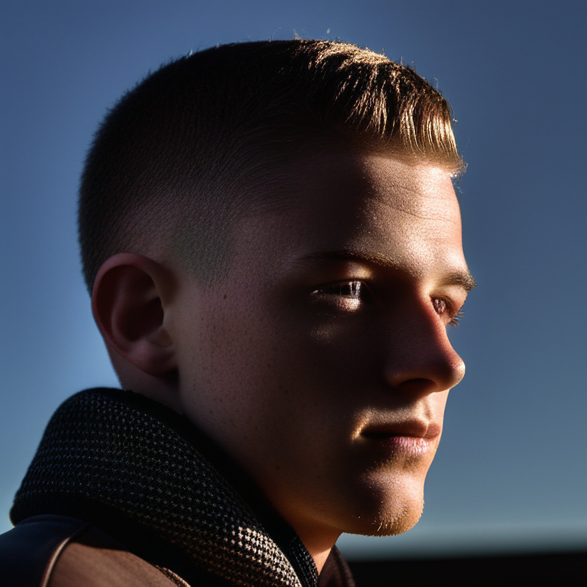 This image showcases a perfectly cut low fade hairstyle, perfect for adding a touch of modernity to your look. The seamless blend between the shaved top and longer hair on the back and sides creates a stylish and effortless appearance. The young man in this photo exudes confidence and self-assurance, making it an inspiring example of how to rock a low fade haircut.