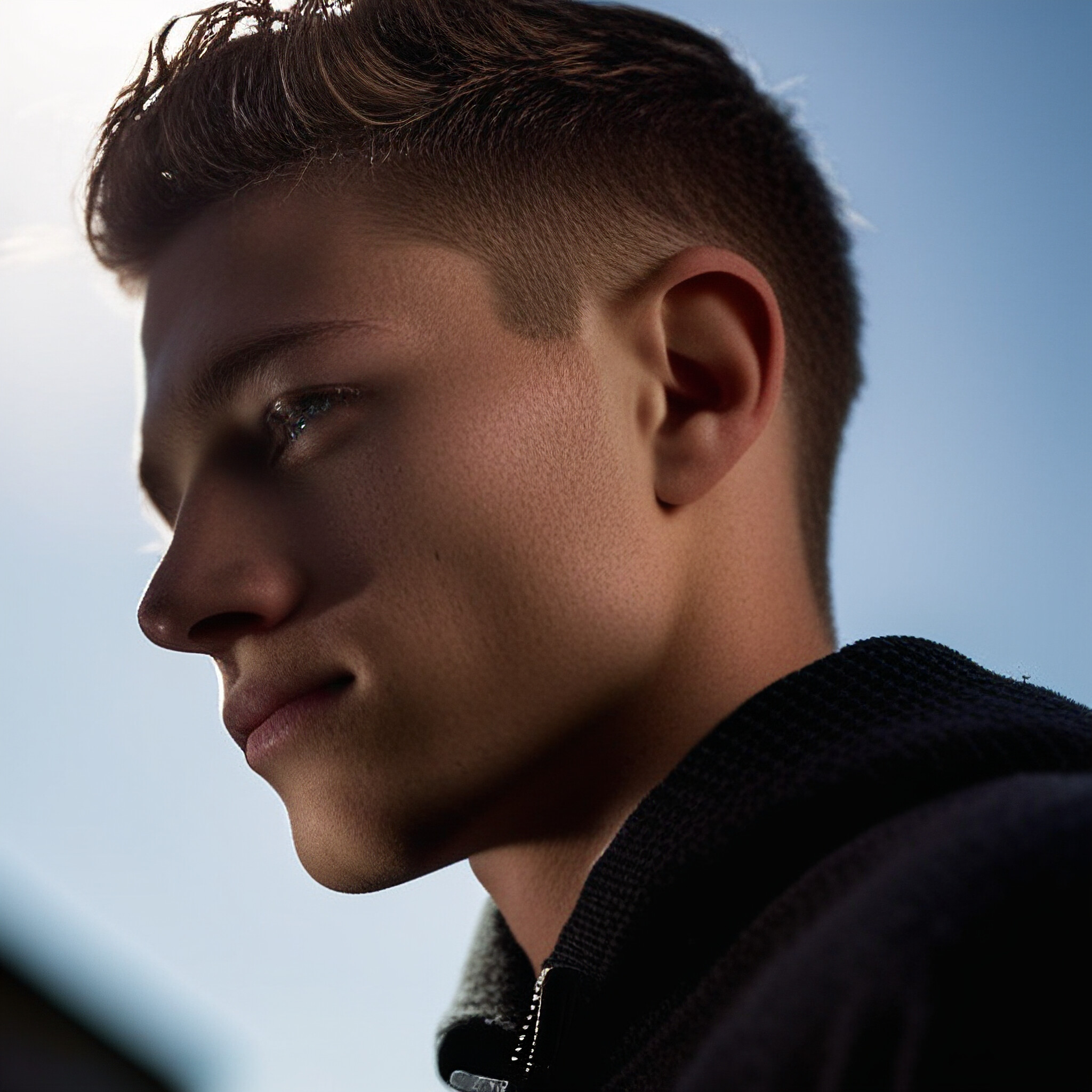 Get ready to be inspired by this stunning image of a young man's low fade hairstyle! Notice the neat and tidy haircut on top, which transitions seamlessly into a longer and more textured cut towards the back of his head. The result is a stylish and modern look that's sure to turn heads.