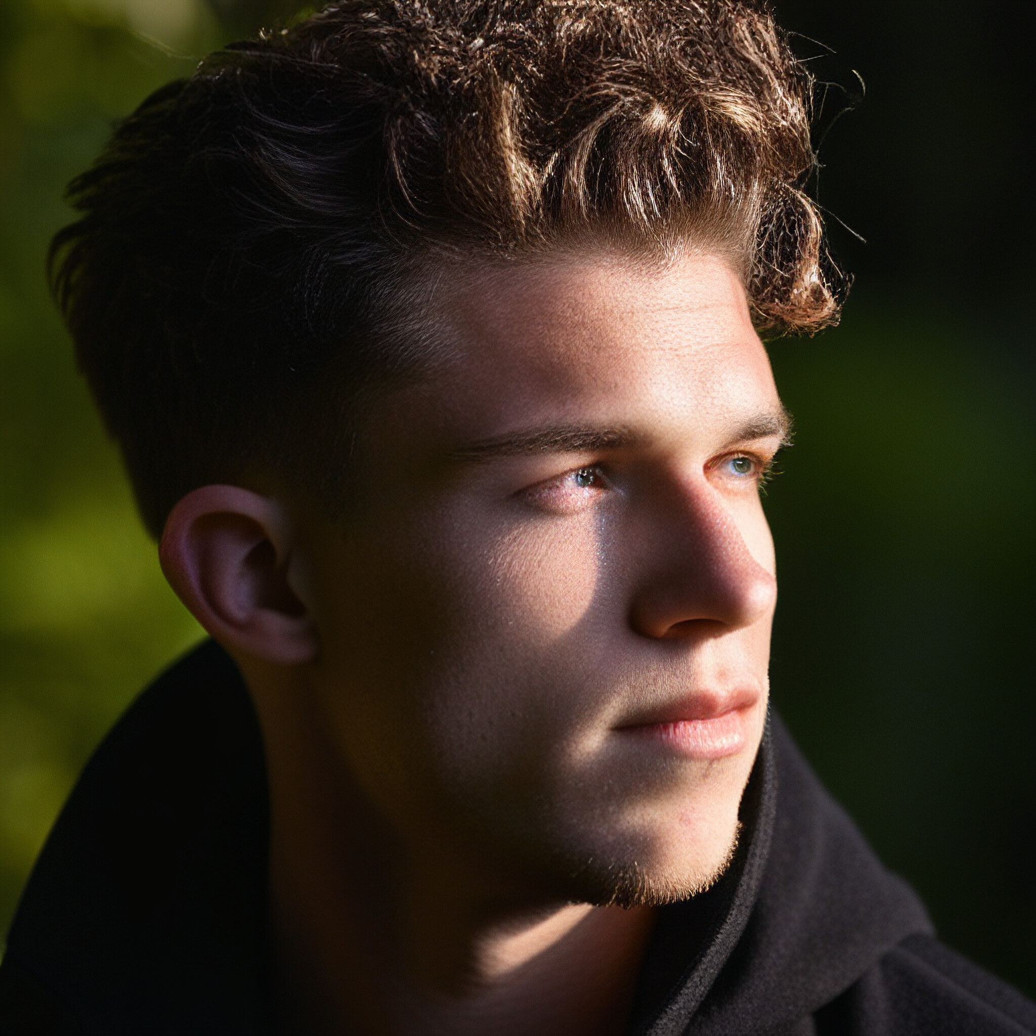 This stunning portrait captures the essence of modern mens' hairstyles. The young man in the image boasts a low fade that starts just above his crown and transitions smoothly into very short hair at the back of his head. This style is all about contrast, creating a striking visual effect that accentuates his features. Notice how the barber or stylist has carefully maintained clean lines and even fading, giving the impression of precision and attention to detail. The image is sure to inspire anyone looking for a fresh new 'do.